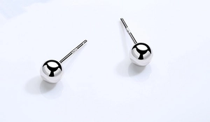 Gros plan sur des boucles d'oreilles boules en argent S925 poli avec poinçon visible