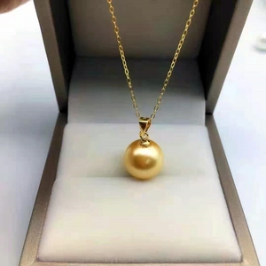 Macro detail of round golden pearl pendant with mirror luster in a grey jewelry box