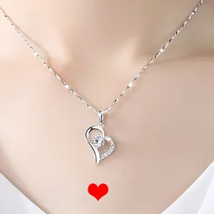 Close-up of 925 sterling silver heart necklace with sparkling zircon pendant on model