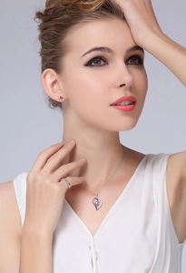 Elegant jewelry set including heart necklace, purple studs and ring on a model