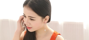 Detail of silver long tassel earrings with sparkling zircon leaf pendant on a model