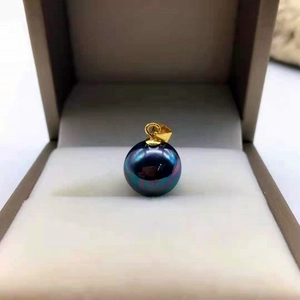 Close-up of a round black shell pearl pendant with iridescent glow in a jewelry box