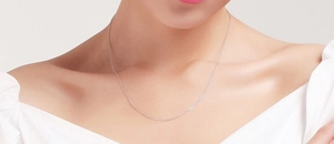 Close-up of a 1.5mm wide sterling silver cross chain worn on the model's collarbone