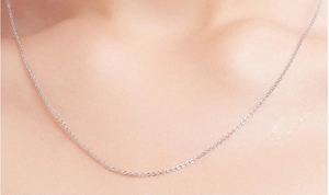 Close-up of a minimalist S925 sterling silver thin link chain on a woman's collarbone