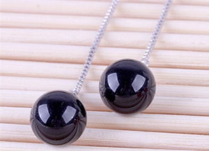 Macro view of 925 silver thread earrings with polished black agate beads and box chains