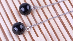 Close-up of 925 sterling silver drop earrings with long box chains and black onyx beads