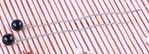 Detailed view of 925 sterling silver threader earrings with black agate beads on bamboo