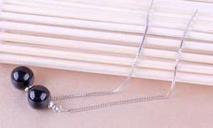 Macro detail of 925 sterling silver tassel earrings with polished black onyx bead pendants