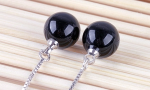 Macro shot of 925 silver box chain tassels with polished black agate beads on bamboo