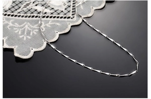 Macro detail of high-polish S925 sterling silver chain on a black reflective background