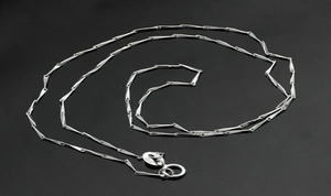Close-up of S925 sterling silver stamp and spring clasp on a minimalist bar chain necklace