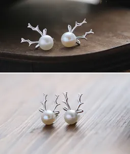 Detail of S925 sterling silver reindeer antler earrings with white pearls on wood