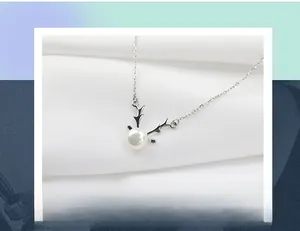Detailed view of S925 silver reindeer antler necklace with a freshwater pearl on white fabric