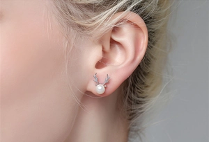 Close-up of S925 silver reindeer antler stud earrings with pearls worn by a model
