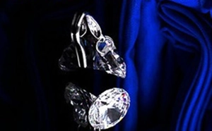 Macro view of pear-cut clear crystal earring with silver hook on blue silk fabric
