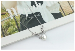 Macro detail of S925 silver reindeer antler necklace with a round white freshwater pearl
