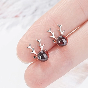 Detail of 925 sterling silver reindeer earrings with garnet red stones shown on fingers