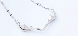 Macro view of polished silver reindeer antler pendant with a delicate link chain