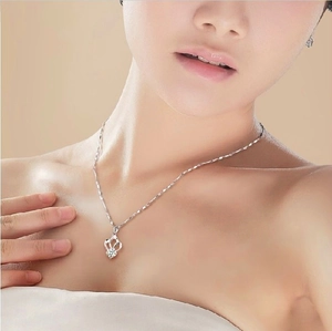 Close-up of 925 sterling silver crown pendant necklace with white gemstone on neck