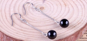 Close-up of 925 silver long tassel earrings with black onyx beads on a wooden background