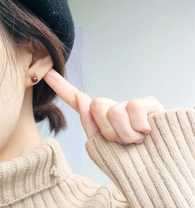 Macro detail of red bead deer antler earrings worn by a model in a cozy winter setting