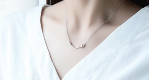 Close-up of a model wearing a silver minimalist deer antler pendant necklace