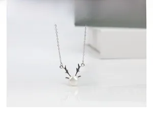 Detail showing an S925 silver reindeer antler necklace with a round white freshwater pearl