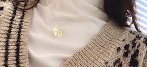 Détail d'un collier pendentif carte du monde doré porté par un mannequin en léopard