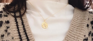 Gros plan du collier avec pendentif carte du monde en argent doré porté au cou