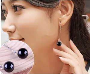 Macro detail of long silver tassel earrings with round black onyx stones and delicate chains