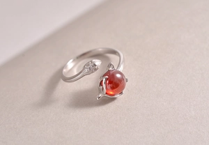 Macro view of adjustable silver ring with red gemstone and small leaf-shaped diamonds