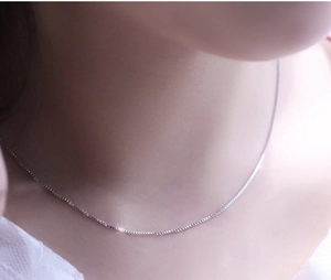 Gros plan d'une délicate chaîne vénitienne en argent sur un modèle en dentelle