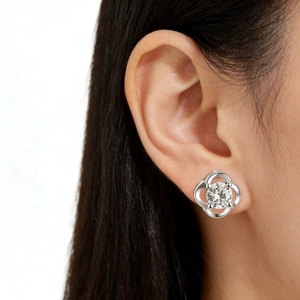 Detail of hollow silver clover earring with central sparkling stone worn by a model