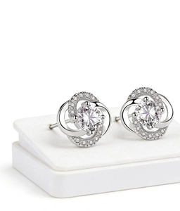 Vue macro de boucles d'oreilles fleur en argent S925 avec zircon central et pétales pavés