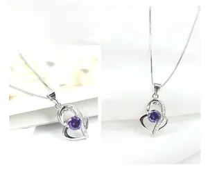 Detail of silver double heart pendant featuring a purple gemstone and white zircon accents