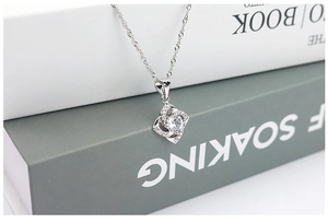 Macro shot of S925 silver clover necklace with clear zircon pendant on minimalist books