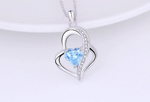 Detailed macro shot of 925 silver heart necklace with blue gemstone and pavé accents
