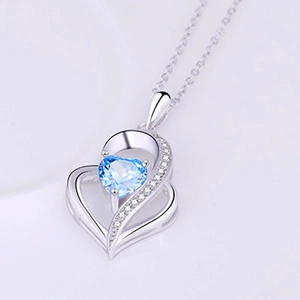 Macro view of blue heart-shaped gemstone necklace with silver pavé frame detail