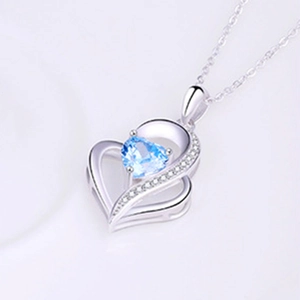 Detail of 925 silver heart necklace featuring a blue gemstone and pavé crystal accents