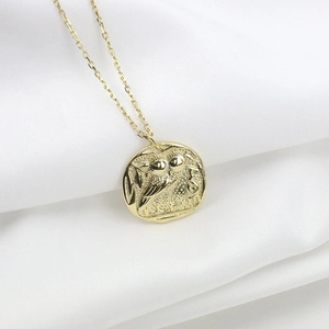 Collier en argent 925 doré avec pendentif pièce chouette en relief sur tissu blanc froissé