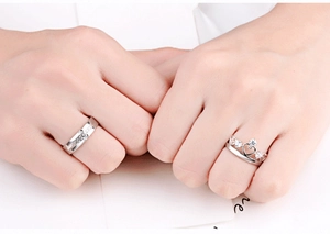 Close-up of s925 silver crown and cross pattern couple rings worn on fingers