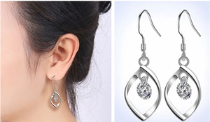 Detail of twisted S925 silver earrings with clear cubic zirconia on a female model