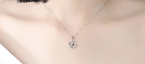 Close-up of S925 sterling silver spinning clover necklace worn on model neck
