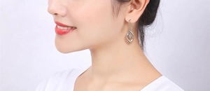 Detail of silver twisted teardrop earrings with central zircon on a female model