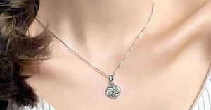 Close-up of S925 sterling silver spinning clover necklace worn on collarbone