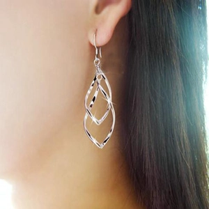 Gros plan de boucles d'oreilles feuilles en argent S925 portées par une femme