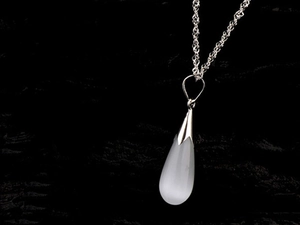 Gros plan du collier pendentif opale en goutte avec chaîne en argent sur pierre noire