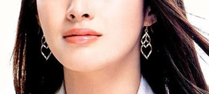 Gros plan de boucles d'oreilles pendantes en forme de feuilles dorées sur un modèle