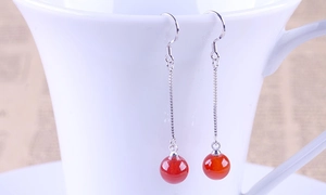 Detail view of S925 silver hook earrings with natural red agate beads on a white cup