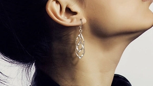 Gros plan d'un mannequin portant des boucles d'oreilles feuilles en argent S925 à glands